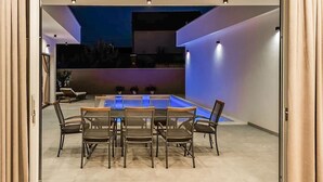 Un espace de restauration extérieur moderne, doté d’une table de billard, de chaises et d’un éclairage d’ambiance.
