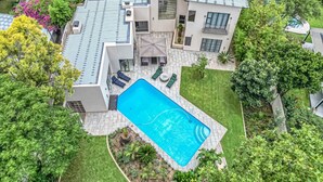 Une maison moderne dotée d’une piscine, de panneaux solaires et d’un jardin bien entretenu.