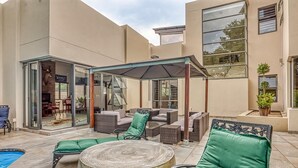 Une terrasse extérieure avec des sièges, une piscine et un espace abrité.
