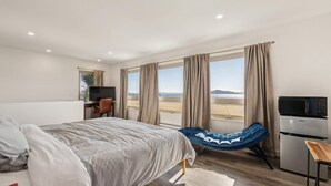 Una camera da letto con un letto, una scrivania, una sedia, un divano, una TV, un forno a microonde e vista sul deserto.