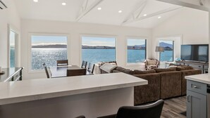 Una cucina moderna con un'isola grande, un'area pranzo con vista e un soggiorno con divano e TV.