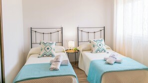 Une chambre d’hôtel avec deux lits, chacun doté d’une tête de lit, d’une table de chevet avec une lampe et d’une petite plante en pot.