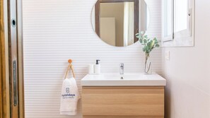 Une salle de bain avec un meuble-lavabo en bois, un miroir, un évier, une serviette et une petite plante.