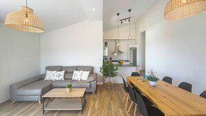 Ein modernes Wohnzimmer mit einem grauen Sofa, einem Holztisch und einem Essbereich mit Tisch und Stühlen.
