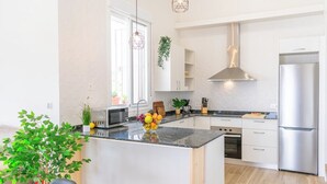 Eine moderne Küche mit weißen Schränken, Edelstahlgeräten, einer großen Kochinsel und einem Fenster mit Aussicht.