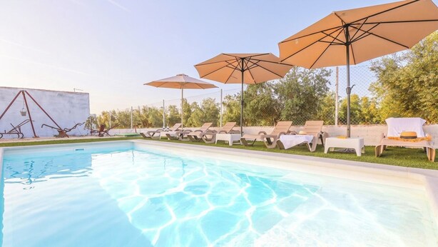 Ein Schwimmbecken mit Liegestühlen und Sonnenschirmen.