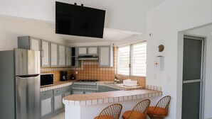 A modern kitchen with a built-in island, stainless steel appliances, and wicker bar stools.