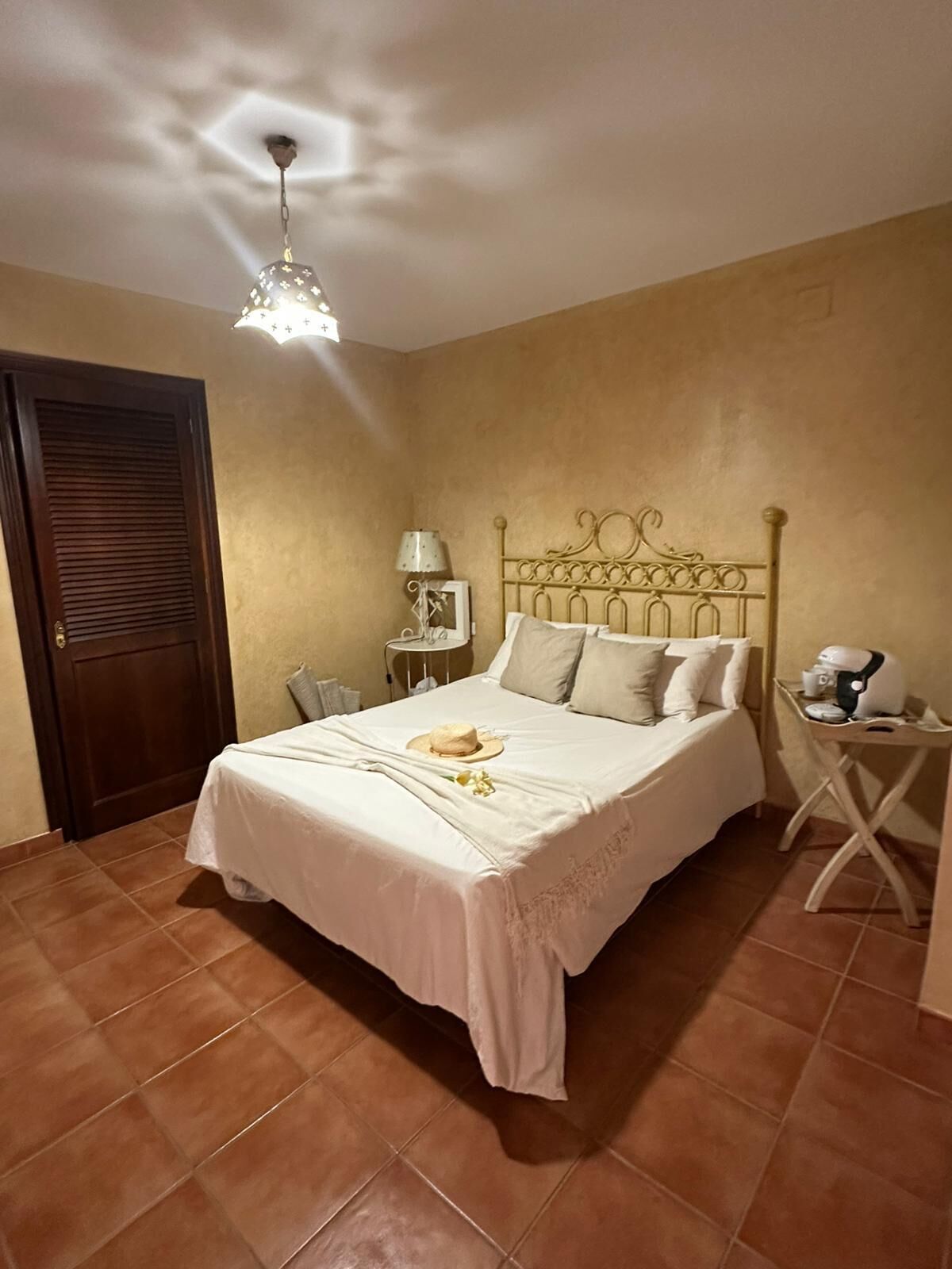 A bedroom with a bed, a nightstand, a lamp, and a ceiling light fixture.