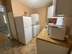 Eine kleine Küche mit Kühlschrank, Herd, Backofen und Geschirrspüler.