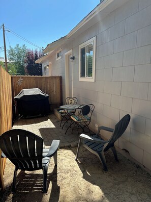 Ein Garten mit Grill, zwei Tischen und Stühlen sowie einem Holzzaun.