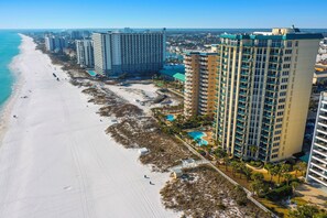 A coastal hotel with multiple high-rise buildings, a beach, and a swimming pool. - Luxury Beachfront Getaway 3BR Sleeps 10 Pool+ Beach Access (Destin)