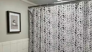 A bathroom with a shower curtain, a framed picture on the wall, and a toilet.