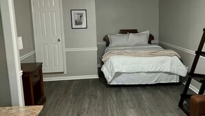 A bedroom with a bed, dresser, and a door.