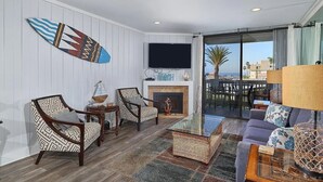 Una sala de estar con chimenea, televisor y vistas al exterior.