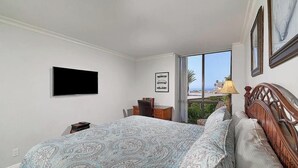 Un dormitorio con cama, escritorio, televisor y ventana con vistas.