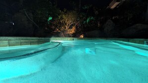 Una piscina interior con agua cristalina, rodeada de formaciones rocosas y árboles.