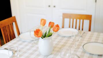 Taula de menjador preparada amb plats, gots i un botic de tulipes.