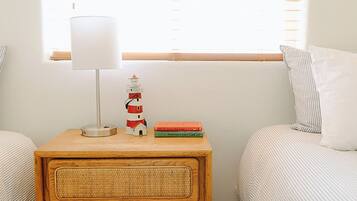 Una camera da letto con comodini in legno, una lampada, una libreria, due letti e una finestra con persiane.