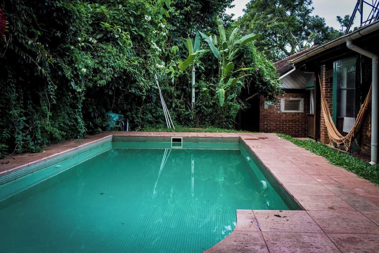 A rectangular swimming pool with a tiled edge, surrounded by a brick patio.