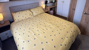 Makuuhuone, jossa on sänky, yöpöydät, peili, vaatekaappi ja hylly, jossa on koriste-esineitä.