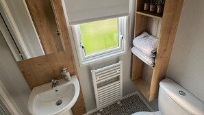 Pieni kylpyhuone, jossa on pesuallas, wc ja pieni ikkuna.