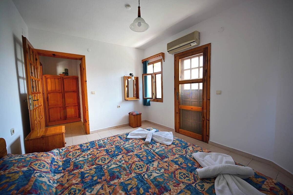 Ein Schlafzimmer mit Bett, Kleiderschrank, Spiegel und Klimaanlage.