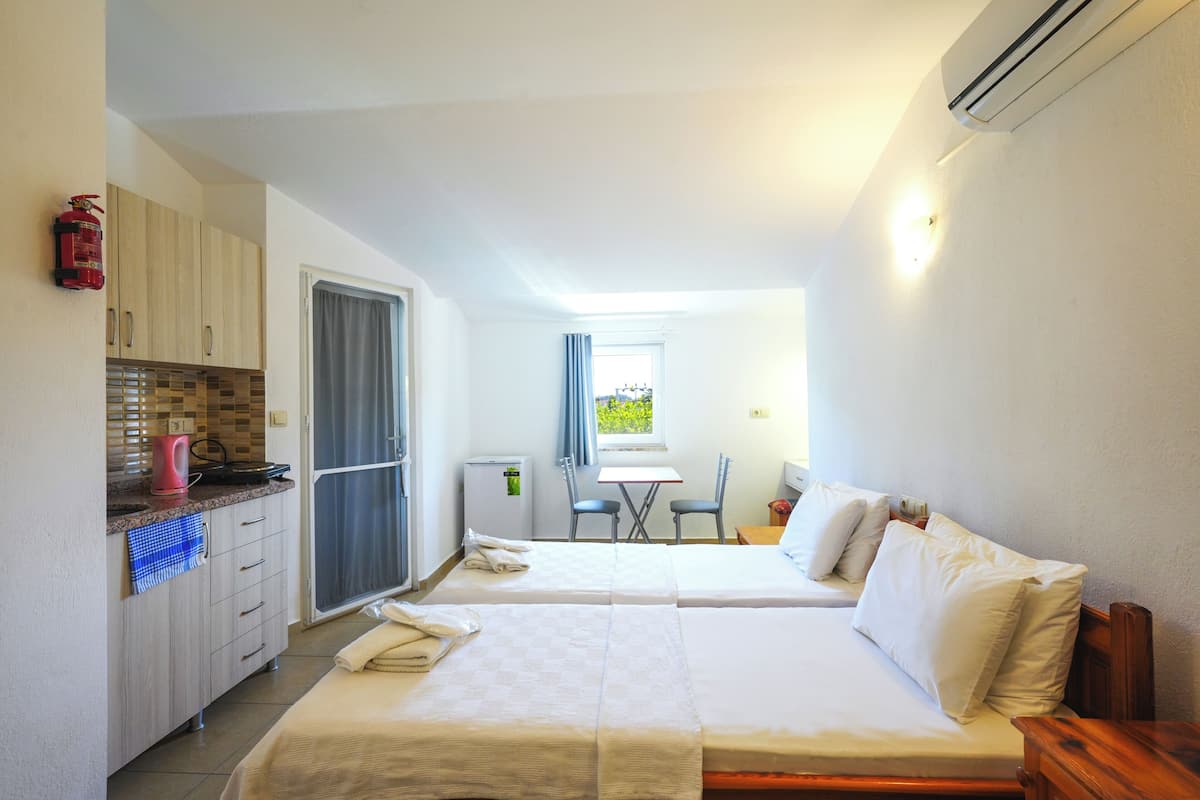 Ein Zimmer mit zwei Betten, einer Küchenzeile, einem Essbereich und einem Fenster.