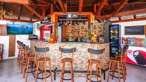 A bar area with a stone counter, wooden chairs, a Coca-Cola fridge, and a television screen. - Şahin Villa Apart (Ortaca)