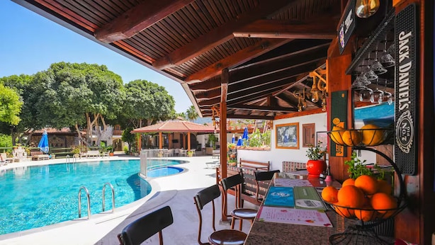 A poolside bar area with a view of a swimming pool, outdoor seating, and a covered patio. - Şahin Villa Apart (Ortaca)