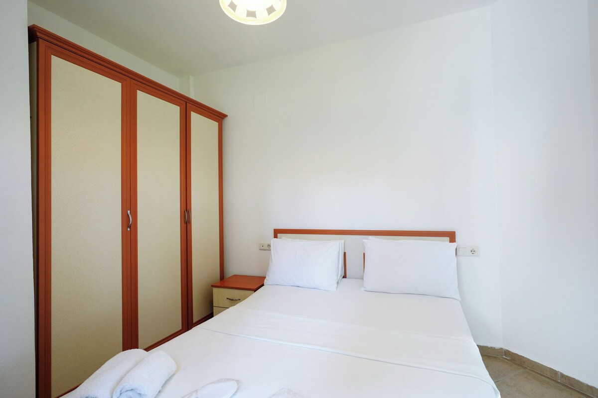 A bedroom with a bed, a nightstand, and a wardrobe.