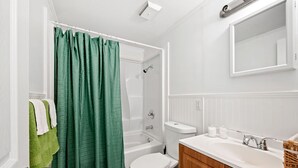 Ein Badezimmer mit Dusche, Toilette, Waschbecken und Spiegel.