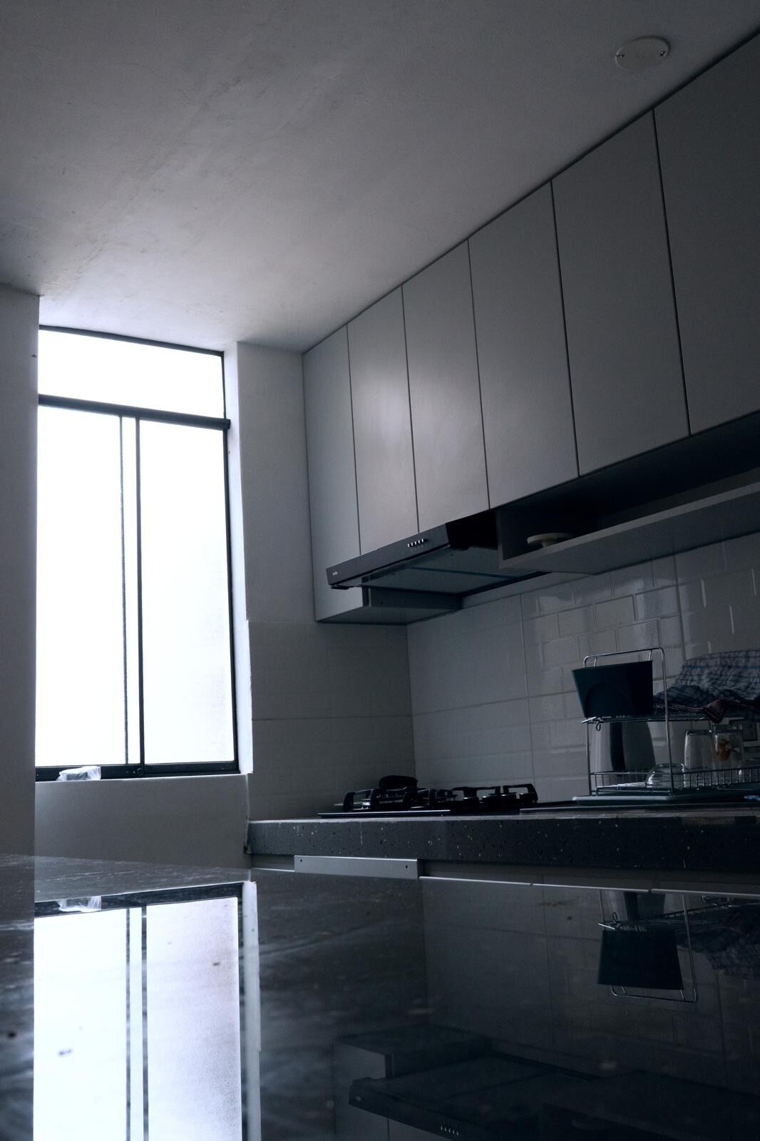 A modern kitchen with a gas stove, stainless steel appliances, and a large window providing natural light.