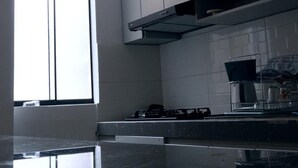 Eine moderne Küche mit Gaskochfeld, Edelstahlgeräten und einem großen Fenster für natürliches Licht.