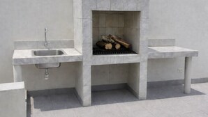 Eine moderne Außenküche mit integriertem Grill, Spüle und einer Sitzbank.