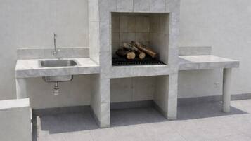 A modern outdoor kitchen with a built-in grill, a sink, and a bench.