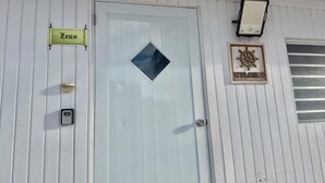 A white door with a window, a 'Welcome' sign, and a 'Zeus' sign. - Beachside Escape | Patio, Pool, Pet-Friendly & BBQ (Cabo Rojo)