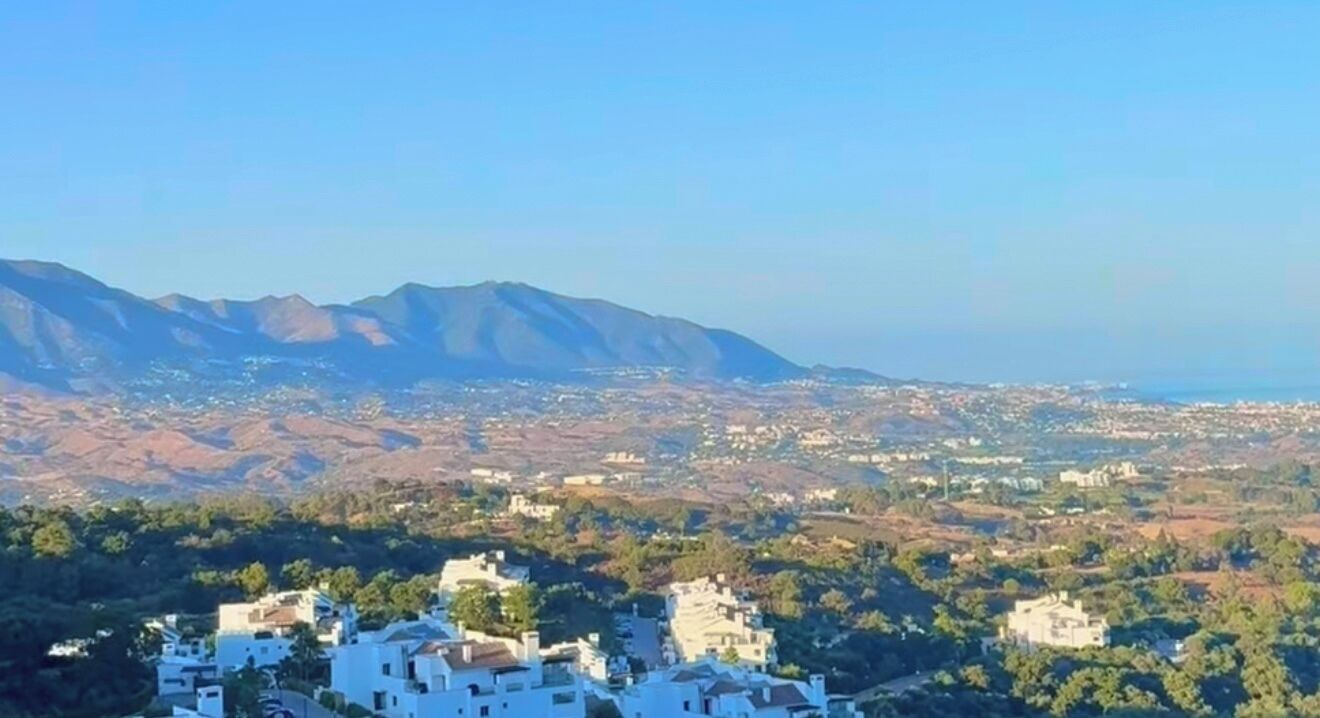 A coastal town with buildings, a mountain range, and a clear sky.