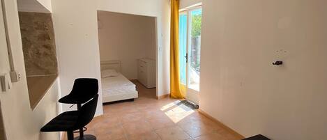 Een slaapkamer met een bed, een stoel en een matras op de vloer.
