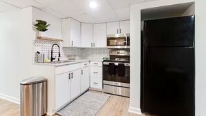 A modern kitchen with white cabinets, stainless steel appliances, and a black refrigerator. - Entire Rental Unit - Cozy 1 BR/ 1 BA (Atlanta)