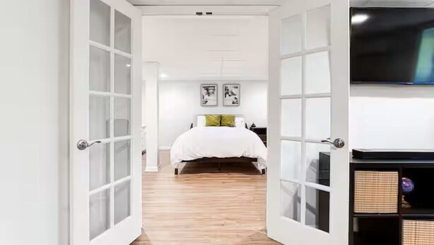 A bedroom with a bed, a TV, and a door leading to another room. - Entire Rental Unit - Cozy 1 BR/ 1 BA (Atlanta)