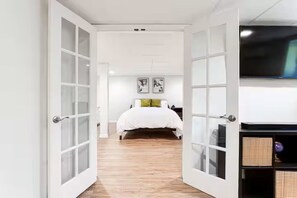 A bedroom with a bed, a TV, and a door leading to another room. - Entire Rental Unit - Cozy 1 BR/ 1 BA (Atlanta)