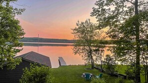 A lakeside property with a dock, a small shed, and a grassy area with outdoor seating.