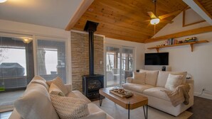 A living room with a fireplace, sofas, a coffee table, and a TV mounted on the wall.