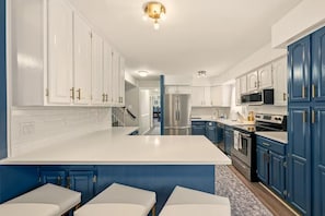 Eine moderne Küche mit weißen und blauen Schränken, Edelstahlgeräten und einer zentralen Kochinsel.