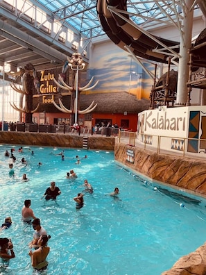 En inomhuspool med en byggnad i form av en grillplats med halmtak, märkt med texten ”Zulu Grille Food”, och en skylt med texten ”Kalahari”.