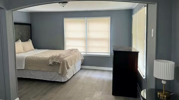 A bedroom with a bed, window blinds, a nightstand, and a lamp. - Entire Unit D - Bold & Exclusive-1BR (Forsyth)