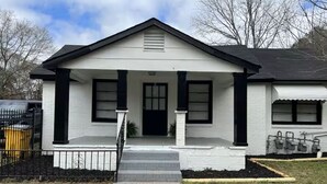 A single-story house with a front porch, a garage door, and a small front yard. - Entire Unit D - Bold & Exclusive-1BR (Forsyth)