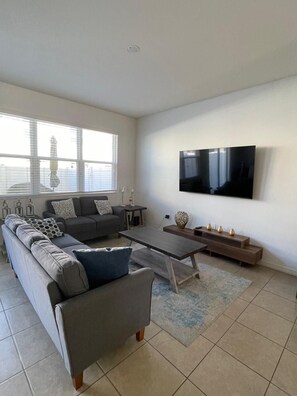 Ein modernes Wohnzimmer mit einer Couch, einem Couchtisch und einem Fernseher.