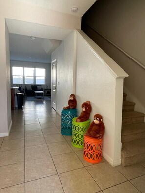 Eine Diele mit Treppe, einer Couch und drei bunten Hockern mit Stofftieren.
