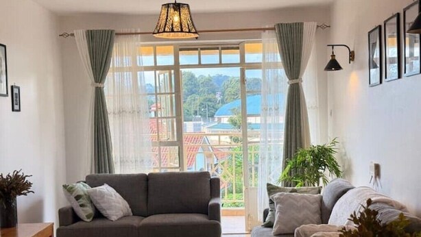 A living room with a sofa, a coffee table, and a view through large windows. - Executive 2 bdrm Apartment Meru, Mt. Kenya region (Meru County)